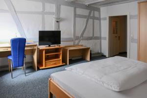 a bedroom with a bed and a desk with a computer at Hotel Haus Landgraf in Walldorf