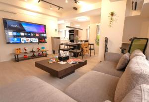 een woonkamer met een bank en een tv bij Modern Tokyo Suites in Tokyo