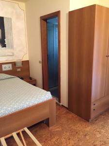 1 dormitorio con 1 cama y armario de madera en Da Rita Hotel, en Condino