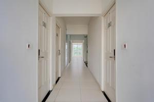 a hallway with white walls and white floors and doors at Super Hotel O KSR Bengaluru City Junction Formerly Gurudev Residency in Bengaluru