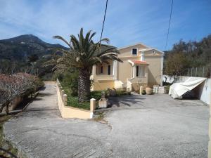 a house with a palm tree in front of a driveway at Palman Othonoi House in Othonoi