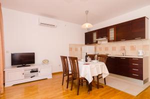 a kitchen with a table with chairs and a television at Apartment Marela in Mokošica