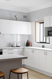 a white kitchen with white cabinets and a table at Budget Single Room in Belmore - Convenient Stay Near Shops - Shared Bathroom in Sydney +20 photos