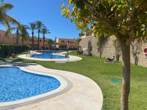 a swimming pool in a park with a tree at Casa con vista al mar in La Marina de la Torre