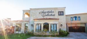 a large white house with a sign on it at Supertubes Guesthouse in Jeffreys Bay