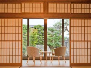 a room with a table and two chairs in front of a window at Kazeno Ryoan Fuga-風乃旅庵 楓雅 in Koshu