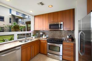 a kitchen with wooden cabinets and stainless steel appliances at Kapalua Bay 31G432B2 FREE CAR KBM Resorts in Honokahua
