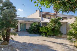 a house with palm trees in front of it at Rescio's Rooms in Cavallino di Lecce