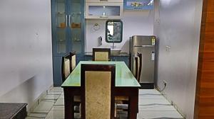 a dining room with a table and chairs and a refrigerator at Sindu Villa in Lucknow