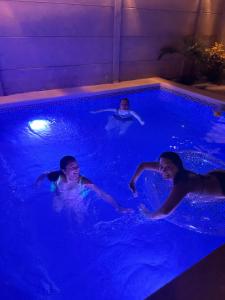 three people are swimming in a swimming pool at Dunamar Beach House in Los Órganos