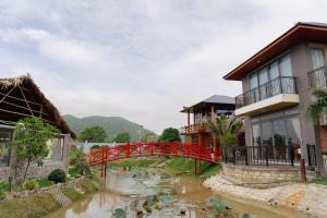 a red bridge over a river with koi at Cafe cắm trại Đồng Gió Phước Hải in Xã Long Mỹ