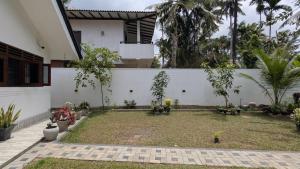 a garden in front of a white building with trees at Waveo Homestay Polhena in Matara