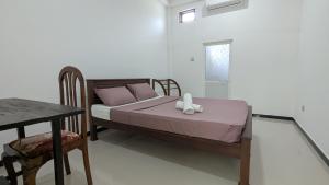 a bedroom with a bed and a table and a window at Waveo Homestay Polhena in Matara