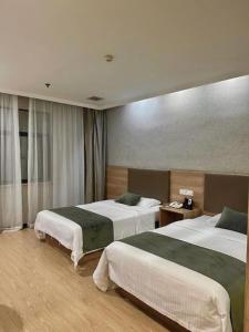 a hotel room with two beds in a room at GreenTree Inn Jiangsu Suzhou Kunshan Beimen Road Express Hotel in Suzhou +204 photos