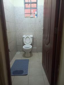 a bathroom with a toilet and a blue mat on the floor at Faith Apartment in Gatunga