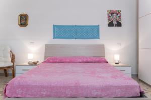 a bedroom with a bed with a pink bedspread at Bene Ennidhos House - Alghero centro storico in Alghero