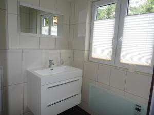 uma casa de banho branca com um lavatório e um espelho em Schwedenhaus im Grünen em Oranienburg