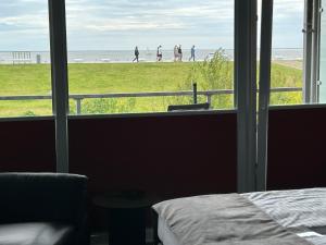 una camera da letto con una finestra con persone che camminano sulla spiaggia di Studio Relax a Büsum