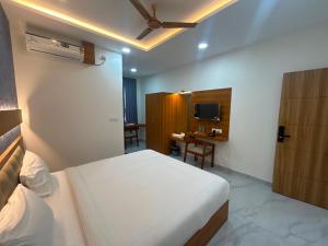 a bedroom with a bed and a desk with a television at Hotel O Golden Stay in Bengaluru