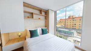 a bedroom with a white bed and a large window at Cabrera 85, Zona T - Elite Flats in Bogotá