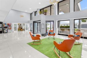 a living room with orange chairs and a green rug at Spark by Hilton Des Plaines Chicago O'Hare in Des Plaines