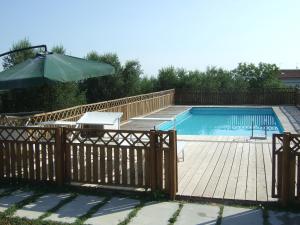 una piscina con recinzione in legno e ombrellone di Agriturismo La Casa della Lavanda - Il Rustico a Marina di Montemarciano