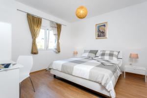 a white bedroom with a bed and a window at Holiday Home Iris in Marina