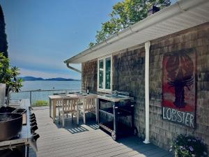 a house with a deck with a table and a grill at Lucky Stone Retreat - private beach & Acadia view in Sullivan