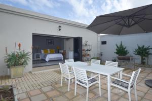 1 dormitorio y patio con mesa blanca y sillas. en Mervue Studio, en Vosburg