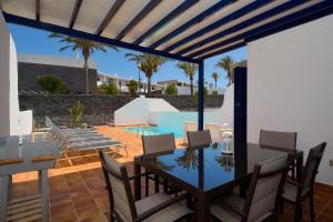 un patio con mesa, sillas y piscina en Villa Oasis, en Playa Blanca