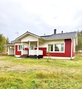 una casa con una casa roja y blanca en Polar Night Wooden House with Sauna, en Sodankylä