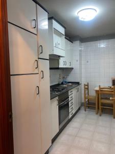 a kitchen with white cabinets and a table with a table at Apartamento Ponte Stay 33 in Ponteareas +3 photos