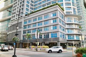 ein weißes Auto, das vor einem großen Gebäude parkt in der Unterkunft Eastwood Legrand3 Studio Type condo in Manila