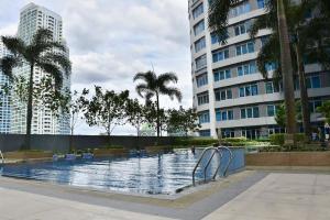 ein Swimmingpool mit Palmen und einem Gebäude in der Unterkunft Eastwood Legrand3 Studio Type condo in Manila