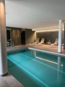 a swimming pool in a hotel with chairs around it at Colle del Giglio Resort & Spa in Ripatransone