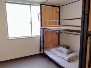 a bunk bed in a room with a window at TONARINO Hostel for Backpackers in Kobe