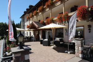 un patio esterno con ombrelloni e sedie di fronte a un edificio di Hotel Rosalpina a Soraga