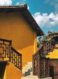 a yellow building with stairs next to a building at Khói Bản Homestay in Dồng Văn