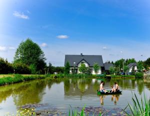 two people are sitting in a boat on a river at Agroturystyka Nad Stawem in Górno