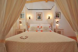 Villagrande StrisailiにあるECO HOTEL ORLANDO Sardegnaのベッドルーム(花の飾られた白い大型ベッド付)