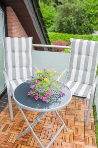 two chairs and a table with flowers on a patio at Aaltine 2 in Bad Bentheim