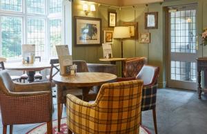 un restaurante con mesas, sillas y ventanas en Dartbridge Inn by Greene King Inns, en Buckfastleigh