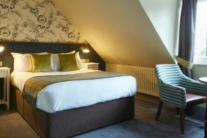 a hotel room with a bed and a chair at Dartbridge Inn by Greene King Inns in Buckfastleigh