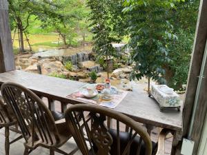 a table and chairs on a porch with a view of a garden at Luxury Treehouse Khaoyai in Ban Nong Makha