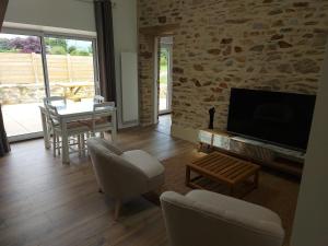 a living room with a television and a table and chairs at Petite maison à la campagne in Ploudaniel
