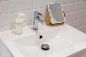 a white sink with a soap dispenser on it at L’Escale – Tout à pied à Ste-Marine in Combrit +12 photos