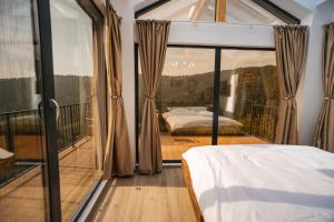 a bedroom with a bed and a large window at Apuseni Air - Luna in Mătişeşti