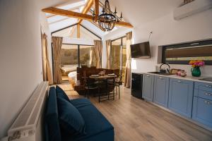 a living room with a blue couch and a kitchen at Cabana romantica cu cer vizibil din pat - Apuseni Air Luna in Mătişeşti