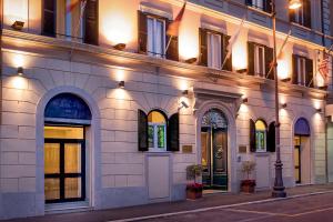 um edifício iluminado com bandeiras à frente em Hotel Diocleziano em Roma