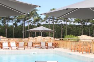 a pool with chairs and tables and umbrellas at Domaine du Ferret Restaurant & Spa in Cap-Ferret